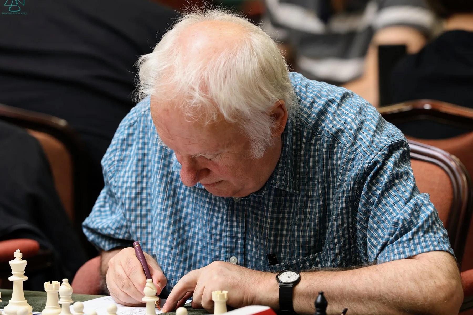 A player at the Tunbridge Wells FIDE Congress writing his move on a scoresheet, with the board and clock beside him.